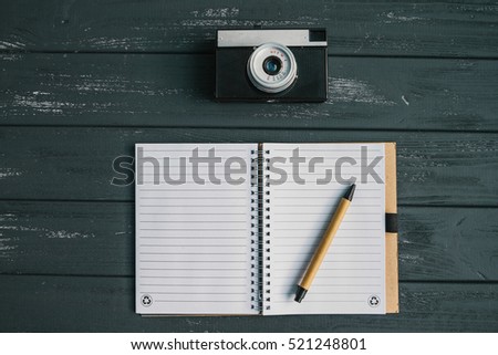 Old retro camera and blank notebook on the gray wooden background