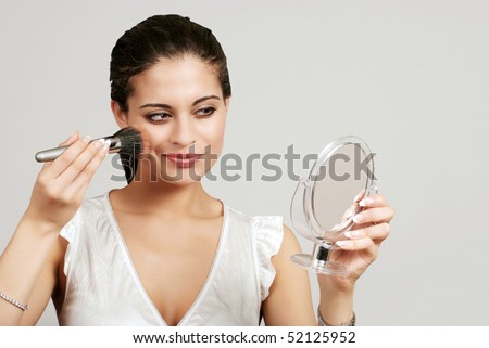 woman putting on makeup with blush brush