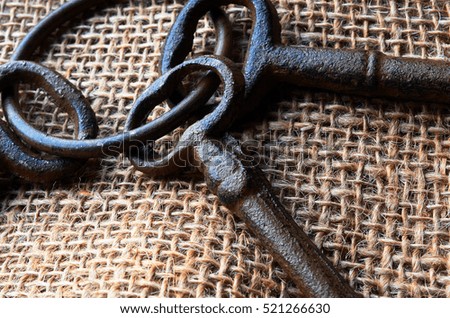A close up image of three vintage keys on burlap and wood.