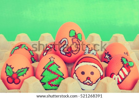 Christmas egg with faces drawn arranged in carton on green background