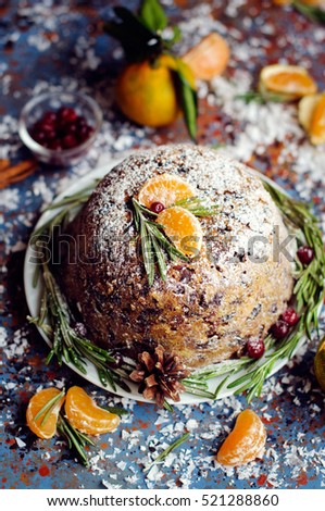 Traditional English Christmas plum pudding, sugar icing, mandarins and berries on blue  vintage background. 