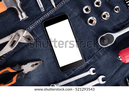 Set of tools and cellphone in grey jeanswear.