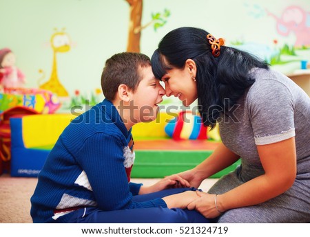 soulful moment. portrait of mother and her beloved son with disability in rehabilitation center Royalty-Free Stock Photo #521324719