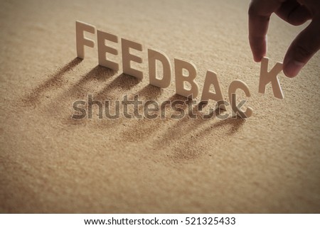 FEEDBACK wood word on compressed board,cork board with human's finger at K letter Royalty-Free Stock Photo #521325433