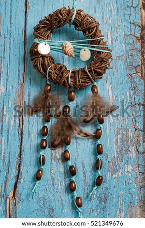 Dream catcher with feathers on blue shabby wooden background. Nautical decor with shells