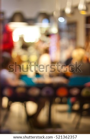 Street with colored lights and lanterns. Showcases cafes and shops, the windows and doors. People in motion in the windows of a cafe. Blurred background, bokeh.