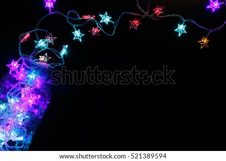 Christmas stars lights background. Holiday shiny garland border spread from glass jar, top view on black. Xmas tree modern glowing decorations, winter holidays illumination