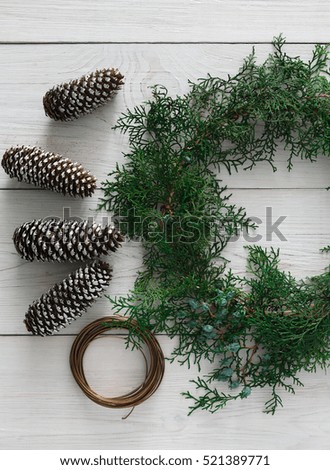 Creative diy craft hobby. Making handmade craft christmas ornaments and thuja tree garland. Home leisure, pine cones and tools for holiday decorations. Top view of white wooden table