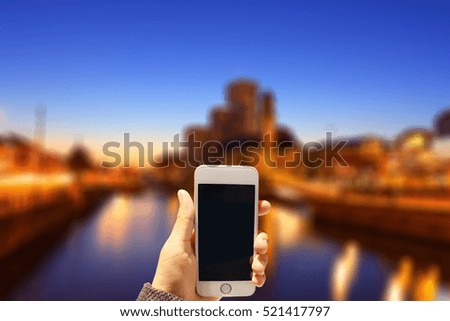 Girl holding her smartphone on the blurred city background. Horizontal