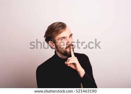 Young man showing finger over lips isolated on a white background