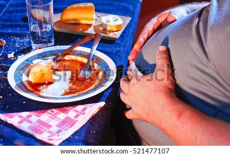 Overweight man resting after eating too much food. Royalty-Free Stock Photo #521477107