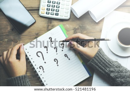 question mark on notebook with woman hand pencil and phone, coffee and calculator on table Royalty-Free Stock Photo #521481196