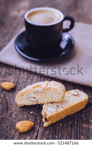 Good morning concept - breakfast frothy espresso coffee accompanied by Italian almond cantuccini biscuits. Traditional italian biscotti cantuccini on wooden table. Selective focus. Toned image.