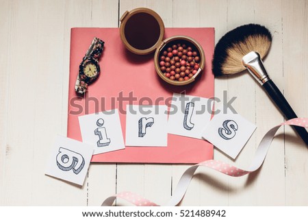 Word "girls" on the pink journal with powder, brush and watch. On white wooden table. Girls mood