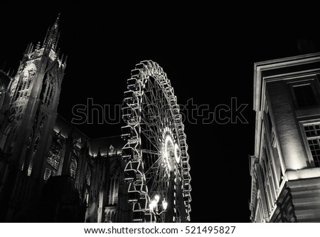 Christmas Ferris wheel in front of the cathedral of Metz. Metz (France). Black and white.