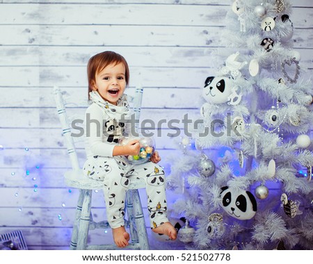 sweet little boy sitting on white chair near Christmas tree