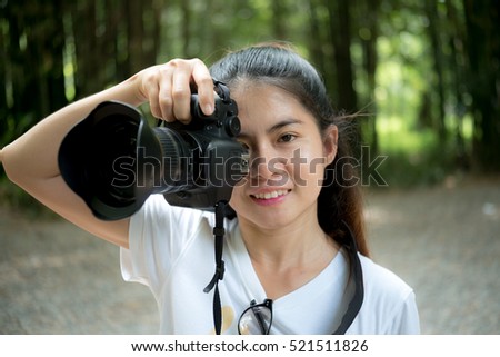 Happy asia woman  on vacation photographing with a dslr camera on the garden and smiling