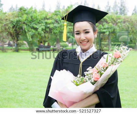 Young woman in graduation gown holding flowers