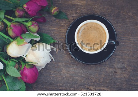 Coffee and flowers peony. A cup of coffee and Peonies on a wooden table. Breakfast on Mothers day, Valentines Day or Women's day. Spring or summer background. Copy space. Top view. Toned image.