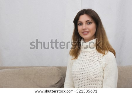 Portrait of young woman sitting on couch in her living room