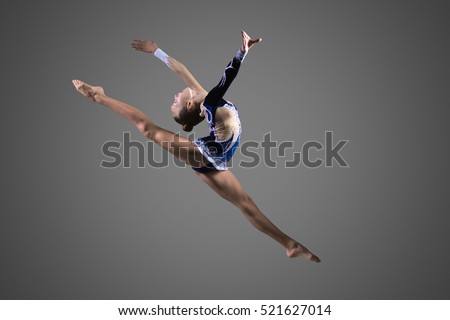 Gymnast girl doing splits in the air. Beautiful cool young fit gymnast woman in blue sportswear dress working out, performing art gymnastics element, jumping, doing split leap in the air, dancing