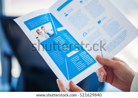 Brochure design. Hands holding a print of a business bi-fold brochure Royalty-Free Stock Photo #521629840