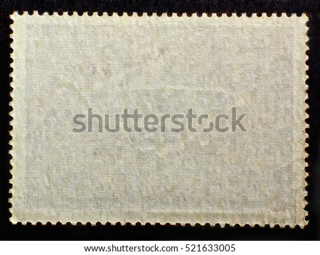 Old grunge posted stamp reverse  side with the edge of the sheet. Texture of paper..  Royalty-Free Stock Photo #521633005