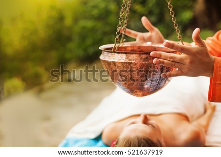 woman getting ayurvedic treatment Shirodara with hot oil pouring on a forehead Royalty-Free Stock Photo #521637919