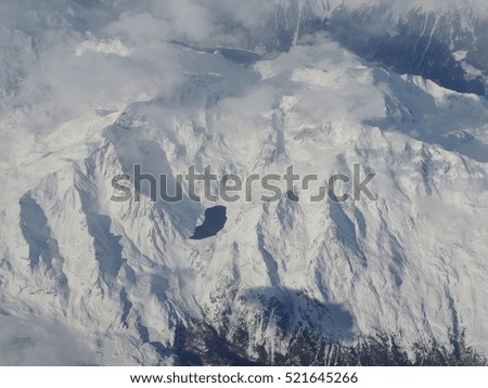 View of an alpine natural lake from airplane during winter season. Aerial photo