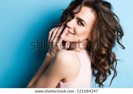 Beauty fashion portrait. Smiling young woman on blue wall background.  Royalty-Free Stock Photo #521684347