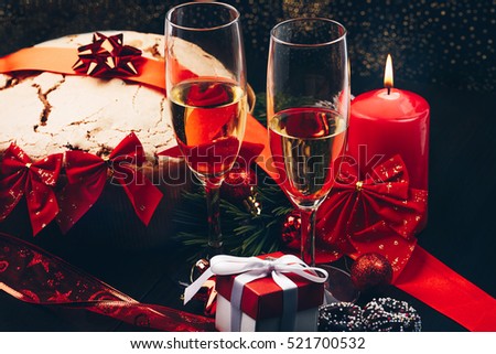 Christmas or New Year. Champagne in glasses with candles, panettone and gift with red satin bow. Copy-space. Festive Concept