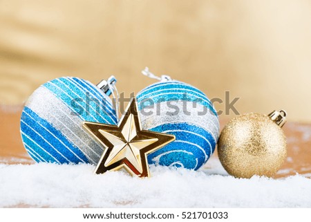 Christmas balls and a star on the snow on a gold background