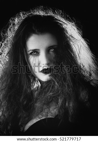 Portrait of a beautiful witch with scary eyes on black background