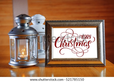 frame on the wooden table with text Merry Christmas. Calligraphy lettering.