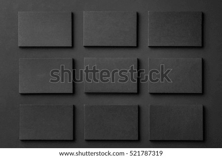 Mockup of horizontal business cards stacks arranged in rows at black textured paper background.