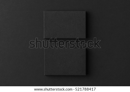 Mockup of two blank business cards stacks at black textured background.