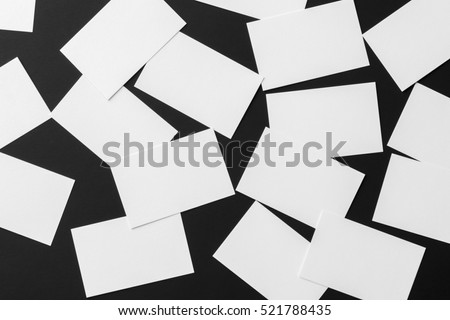 Mockup of scattered white business cards stacks arranged in rows at black textured paper background.