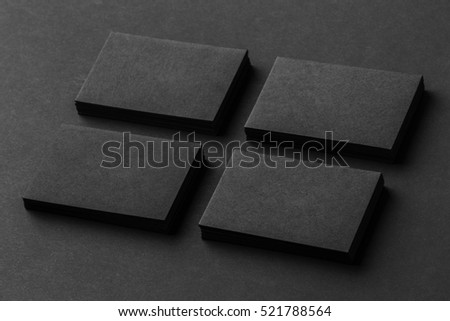 Mockup of four black business cards stacks arranged in rows at black paper background.