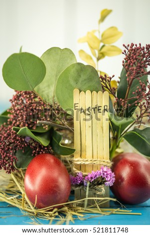 the word Easter in the conceptual block text on wooden sticks, beautiful festive eggs with greens