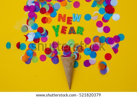 flat lay in yellow background.Ice cone with confetti and new years message