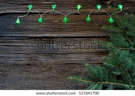 Christmas lights on a wooden background with free space. In the background of twigs Christmas trees.