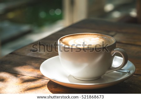 A cup of hot latte coffee on vintage wooden table in cafe
