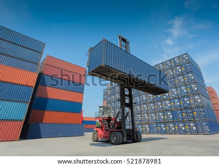 Forklift truck lifting cargo container in shipping yard or dock yard against blue sky with cargo container stack in background for transportation import,export and logistic industrial concept Royalty-Free Stock Photo #521878981