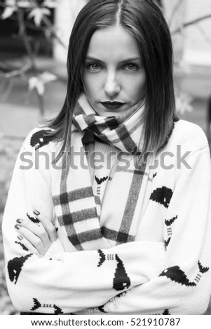 young beautiful girl portrait with natural make up and red lips and short brown hairs in white pullover in street bw