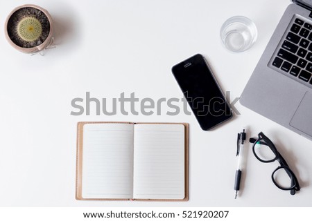 White office desk table with laptop, smartphone, notebook, and glass. Top view with copy space, flat lay.