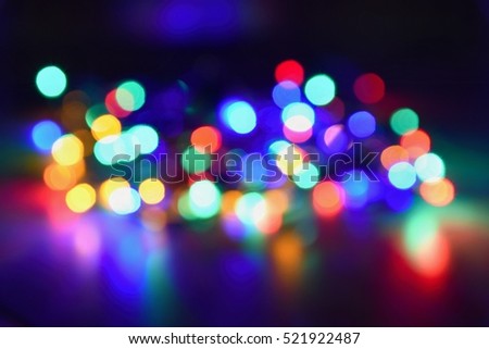 Christmas blurred lights on black background with copy space. Abstract colorful reflections of bulbs on a Christmas tree.
