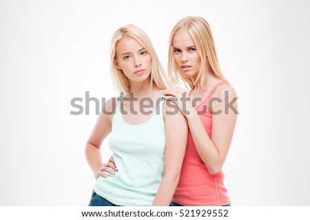 Picture of young ladies dressed in t-shirts and jeans posing. Isolated over white background. Looking at the camera.