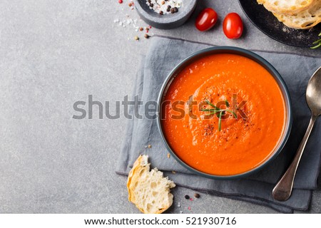 Tomato soup in a black bowl on grey stone background. Top view. Copy space. Royalty-Free Stock Photo #521930716