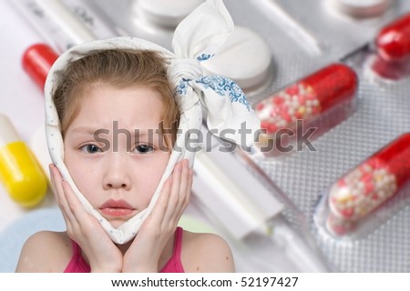 a girl with a bandage around her face, various pills and a glass thermometer in the background Royalty-Free Stock Photo #52197427