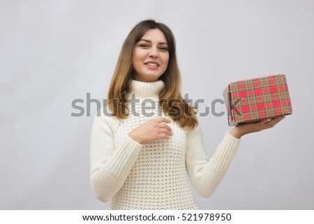 Woman in white sweater holding gift box over gray background